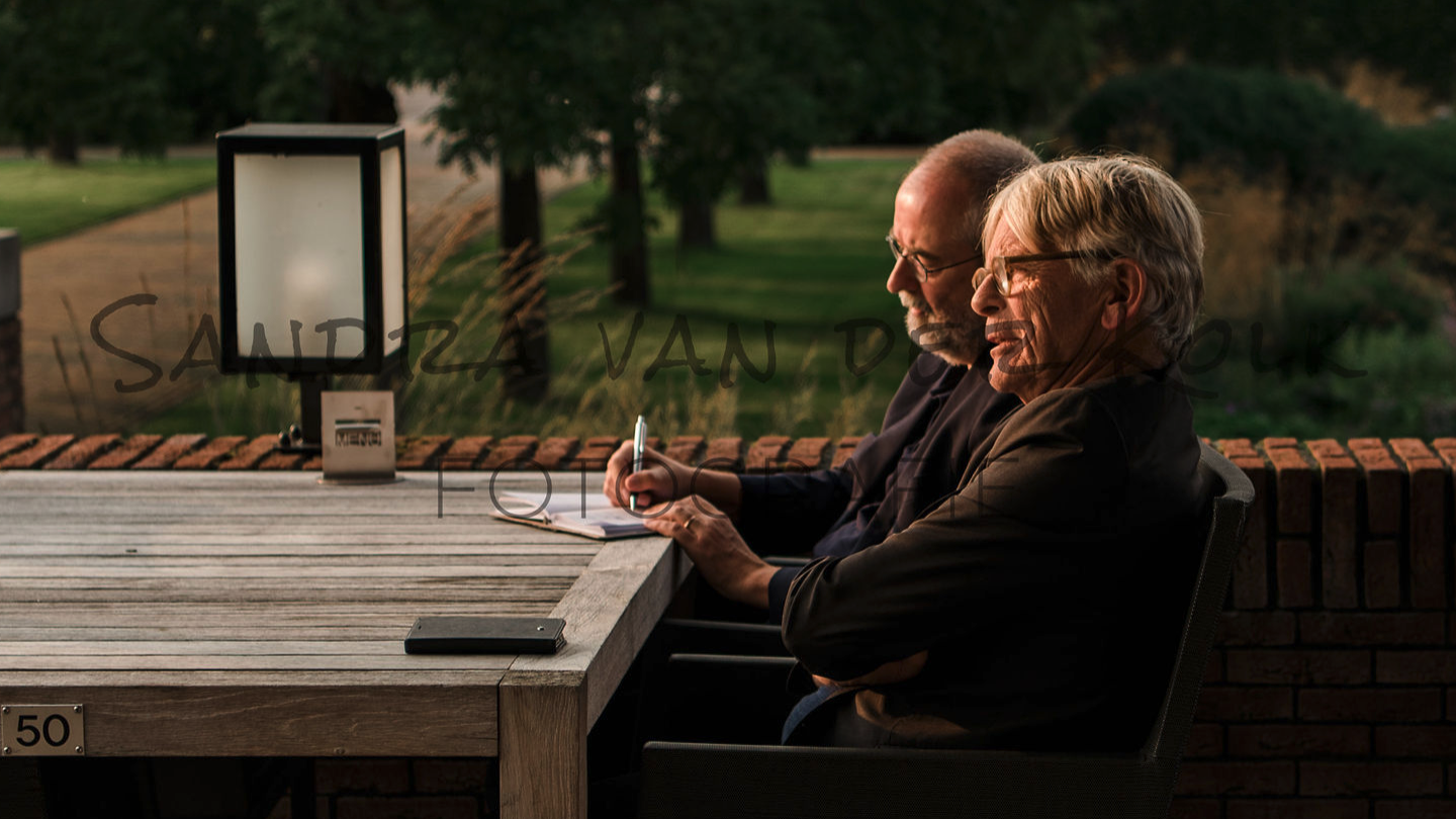 Ronald Giphart en Roland Rozenbroek schrijvend op een bankje